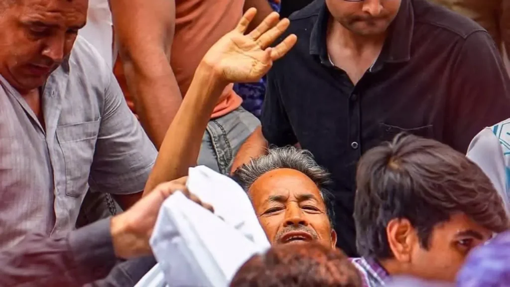 Police personnel carry activist Sonam Wangchuk away during a protest as supporters surround him.